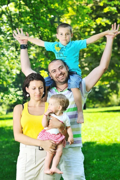 Šťastný mladý pár s dětmi bavit v parku — Stock fotografie