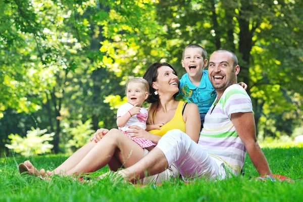 Glückliches junges Paar mit ihren Kindern hat Spaß im Park — Stockfoto