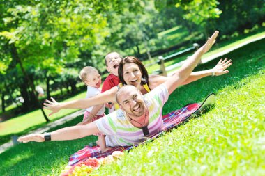 Happy young couple with their children have fun at park clipart