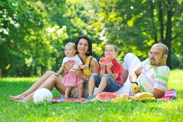 Szczęśliwa młoda para z dziećmi zabawy w parku — Zdjęcie stockowe