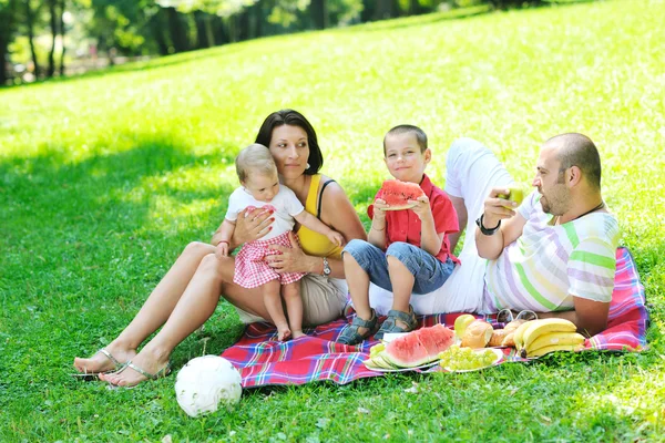 Счастливая молодая пара с детьми развлекается в парке — стоковое фото