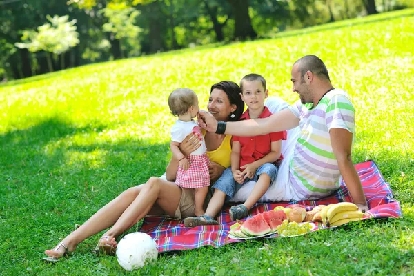 Счастливая молодая пара с детьми развлекается в парке — стоковое фото