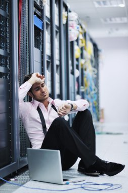 Businessman with laptop in network server room clipart