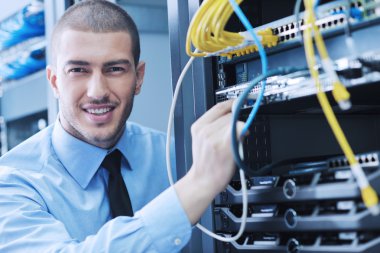 Businessman with laptop in network server room clipart