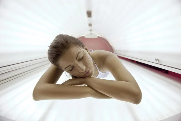 Hermosa joven bronceándose en solarium — Foto de Stock