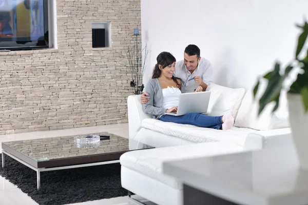 Radosna para zrelaksować się i pracować na laptopie w nowoczesnym domu — Zdjęcie stockowe