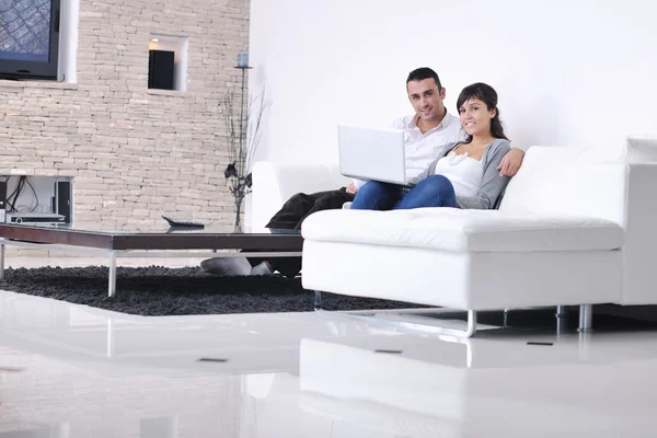 Radosna para zrelaksować się i pracować na laptopie w nowoczesnym domu — Zdjęcie stockowe