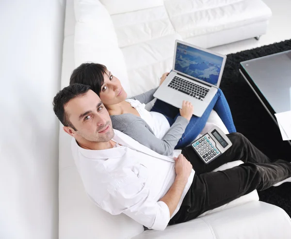 Pareja alegre relajarse y trabajar en el ordenador portátil en el hogar moderno — Foto de Stock