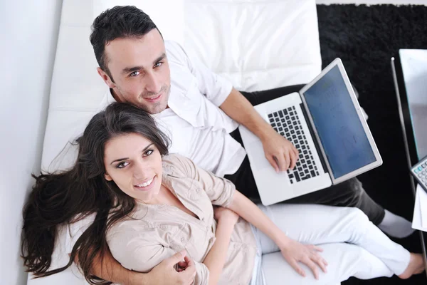 Muntre par som slapper av og jobber med en bærbar datamaskin i det moderne hjemmet – stockfoto