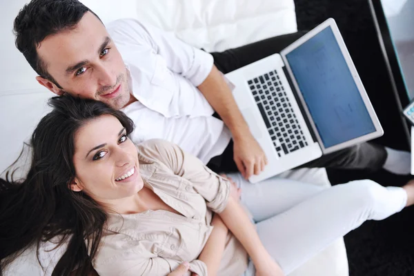 Radostný pár relaxovat a pracovat na notebooku v moderním domě — Stock fotografie