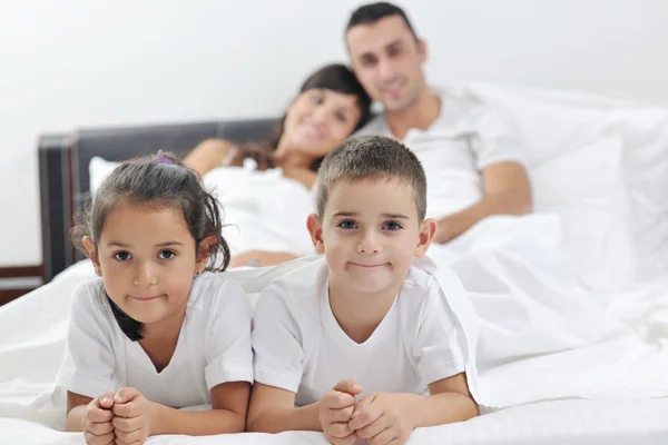 Счастливая молодая семья в спальне — стоковое фото