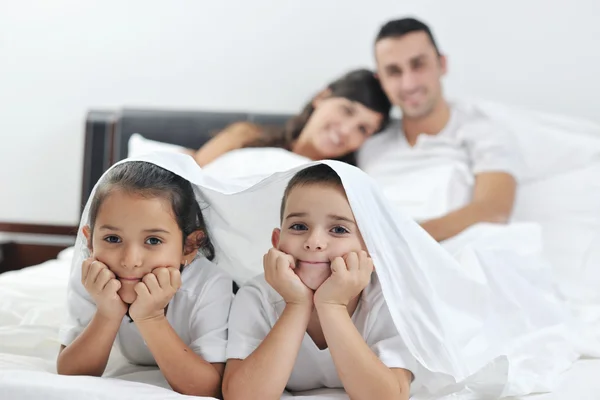 Счастливая молодая семья в спальне — стоковое фото