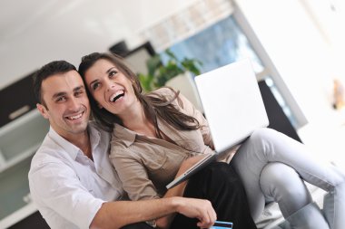 Joyful couple relax and work on laptop computer at modern home clipart