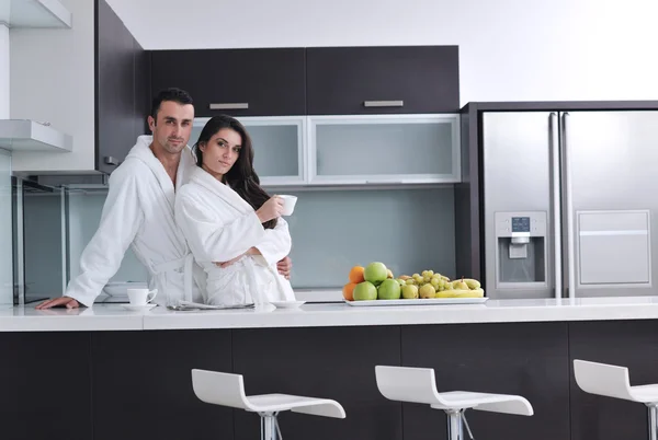 Happy couple reading the newspaper in the kitchen at breakfast — Stock Photo, Image