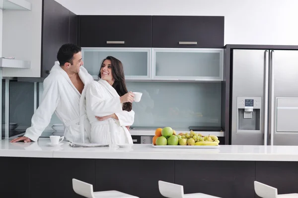 Onnellinen pari lukemassa sanomalehteä keittiössä aamiaisella — kuvapankkivalokuva