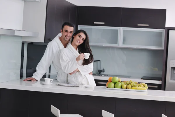 Happy couple reading the newspaper in the kitchen at breakfast — Stock Photo, Image
