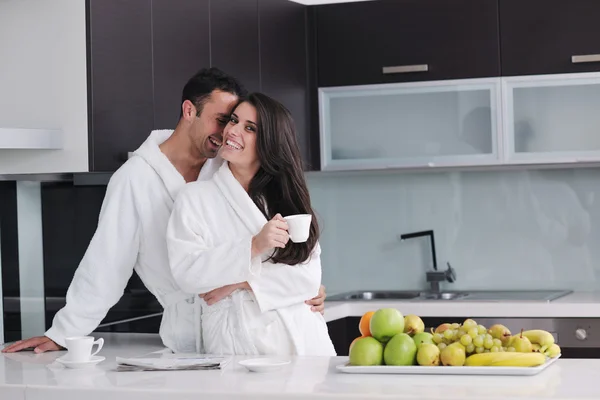 Casal feliz lendo o jornal na cozinha no café da manhã — Fotografia de Stock