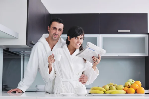 Onnellinen pari lukemassa sanomalehteä keittiössä aamiaisella — kuvapankkivalokuva