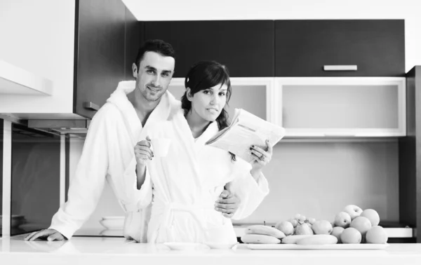 一对快乐的夫妇早餐时在厨房看报纸 — 图库照片