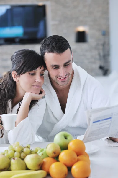 Szczęśliwa para czytająca gazetę w kuchni przy śniadaniu — Zdjęcie stockowe