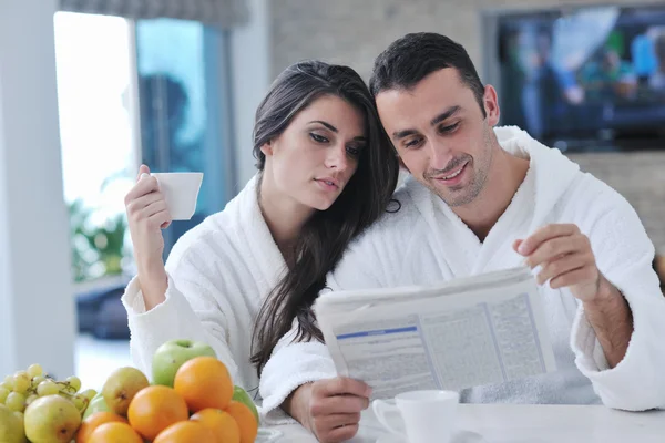 Szczęśliwa para czytająca gazetę w kuchni przy śniadaniu — Zdjęcie stockowe