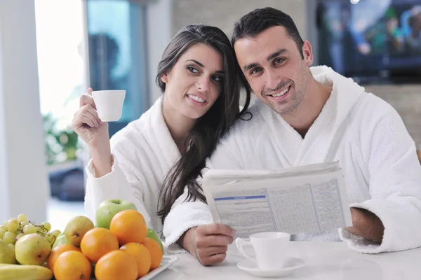 一对快乐的夫妇早餐时在厨房看报纸 — 图库照片