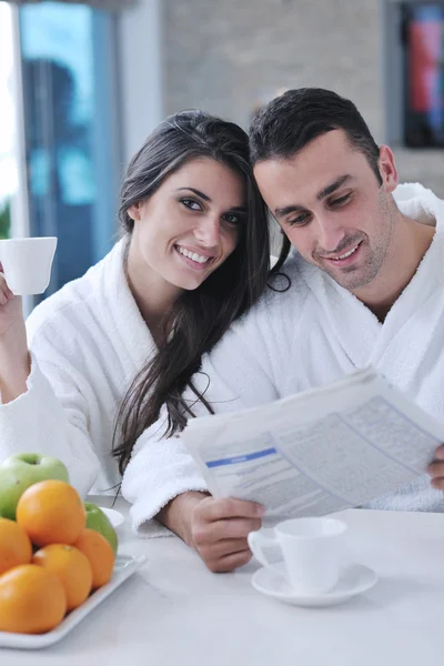 Casal feliz lendo o jornal na cozinha no café da manhã — Fotografia de Stock