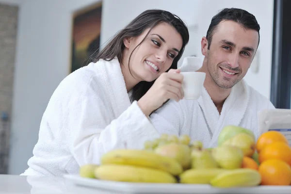 Pareja feliz leyendo el periódico en la cocina en el desayuno —  Fotos de Stock