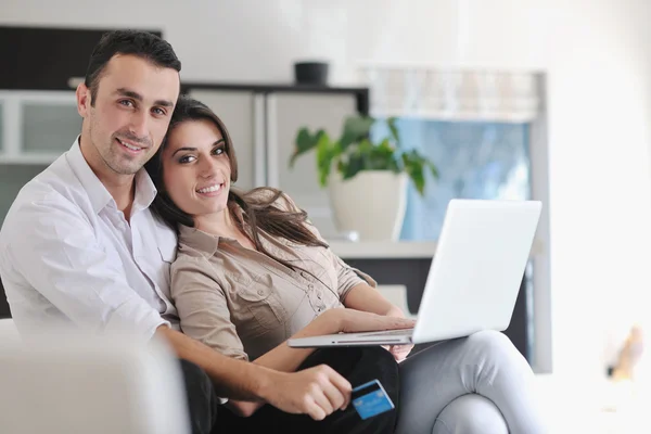 Χαρούμενο ζευγάρι χαλαρώνουν και εργάζονται σε φορητό υπολογιστή στο σύγχρονο σπίτι — Φωτογραφία Αρχείου