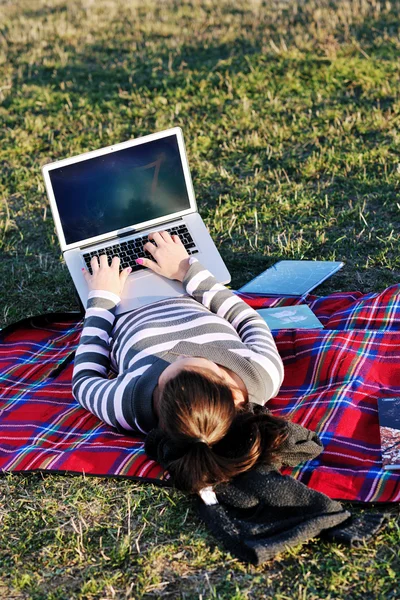 年轻的女孩工作在笔记本电脑上户外 — 图库照片