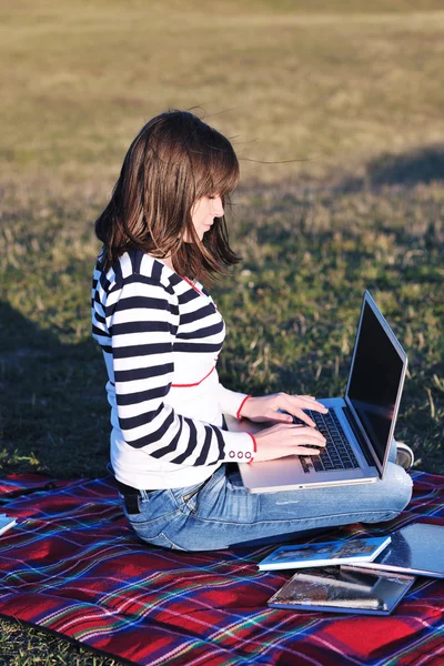 Chica joven de trabajo en el ordenador portátil al aire libre — Foto de Stock