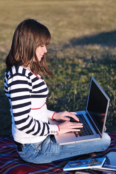 Chica joven de trabajo en el ordenador portátil al aire libre — Foto de Stock