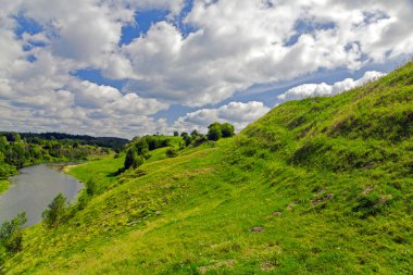 Yeşil tepe ve bulutların altında Nehri