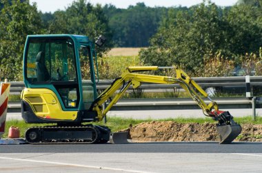 Mini excavator on motorway clipart