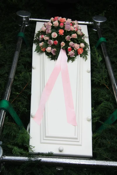 Біла труна з рожевими квітами симпатії — стокове фото