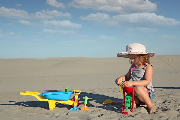 Девочка играет с игрушками в песке — стоковое фото