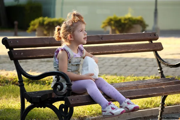 Kleines Mädchen sitzt auf der Bank — Stockfoto