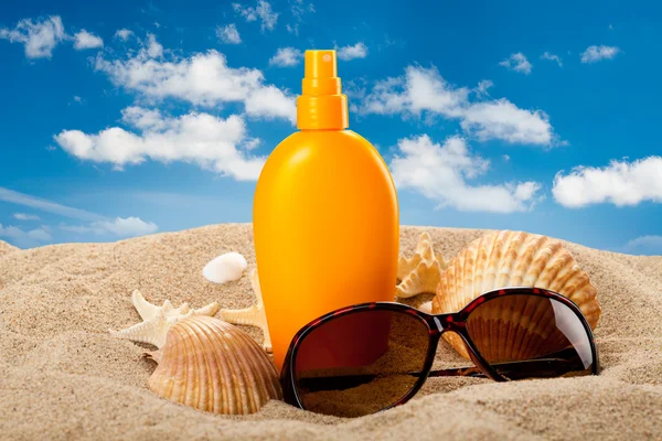 Solbränna olja och mörka glasögon på stranden — Stockfoto