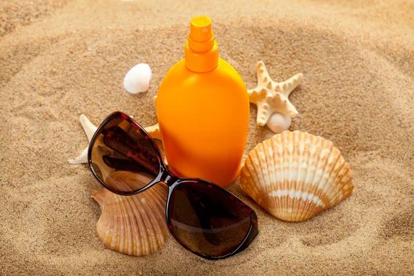 Spiaggia estiva - olio abbronzante e occhiali scuri su sabbia — Foto Stock
