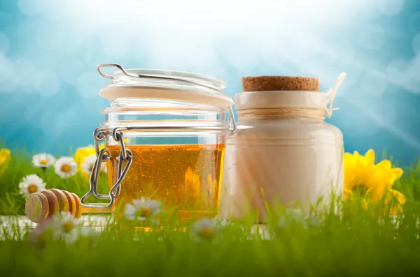 Hälsosam mat - burkar honung och våren blommor — Stockfoto