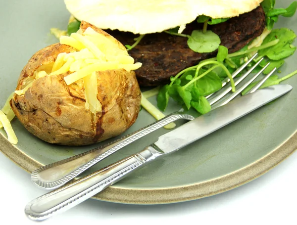 Hamburguesa vegetariana, berro, patata al horno, cuchillo y tenedor — Foto de Stock