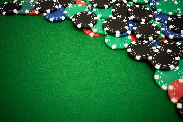 Colorful gambling chips on green felt background — Stok fotoğraf