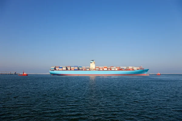 Konténerszállító hajó elhagyná a kikötőt, assist által egy vontatóhajó. — Stock Fotó