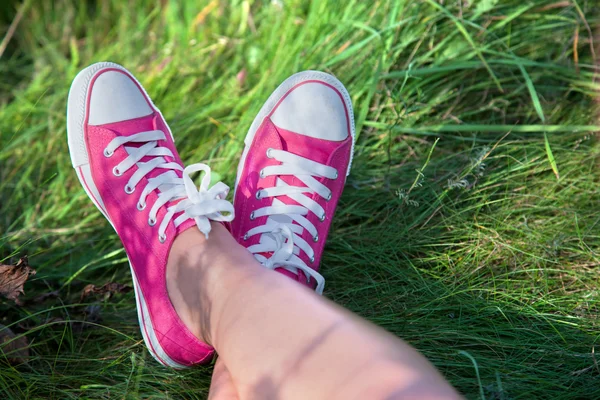 Roze sneakers op meisje benen op gras — Stockfoto