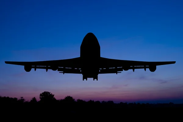 stock image Silhouette of the plane starting on a sunset background.