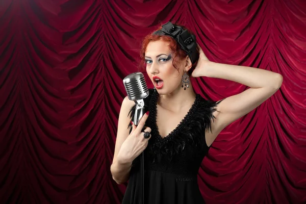 Beautiful redhead woman singing into vintage microphone — Stock Photo, Image