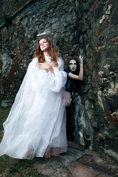 Bruxa e anjo contra as paredes do velho castelo — Fotografia de Stock