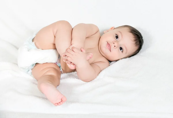 Bebê feliz brincando com seus pés, no fundo branco — Fotografia de Stock