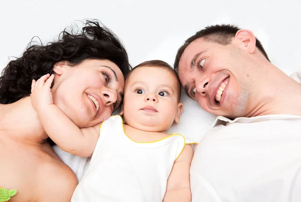 Gelukkige familie, moeder, vader en baby op het witte bed — Stockfoto