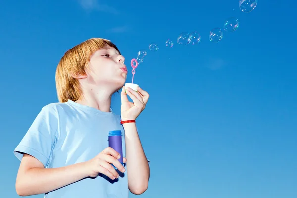 Boy with soap bubbles against a sky — Stock Photo, Image